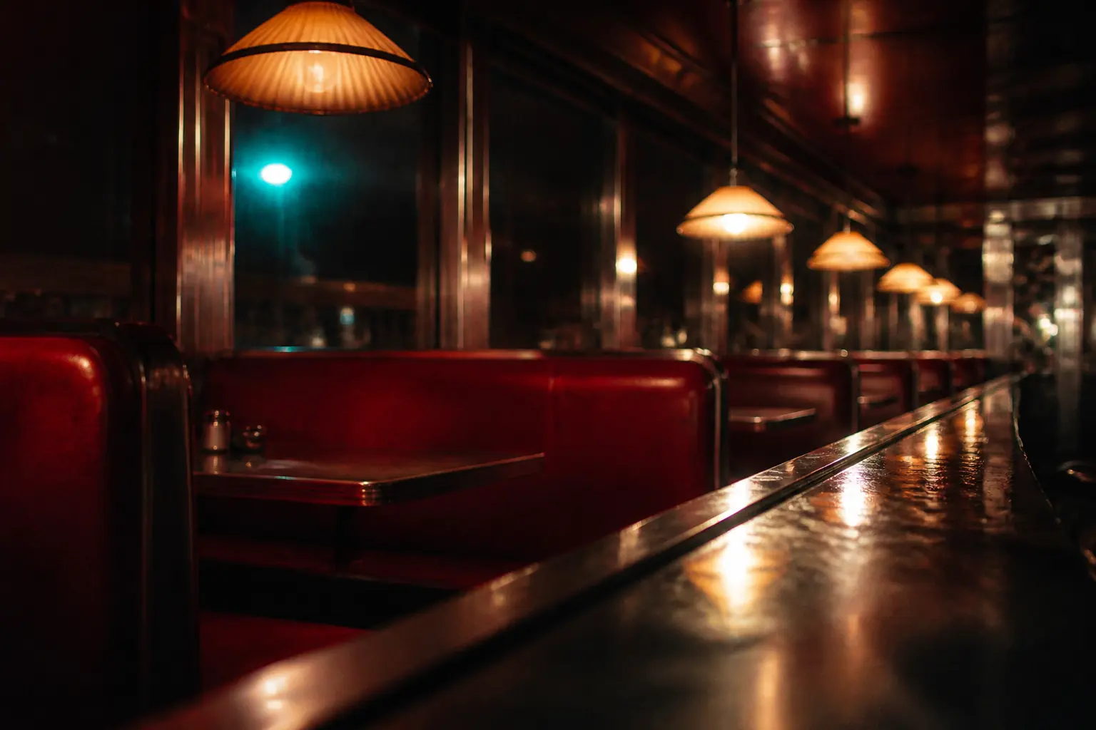 Original artwork of a diner interior at night in saturated red and amber, with a chrome counter edge catching light.